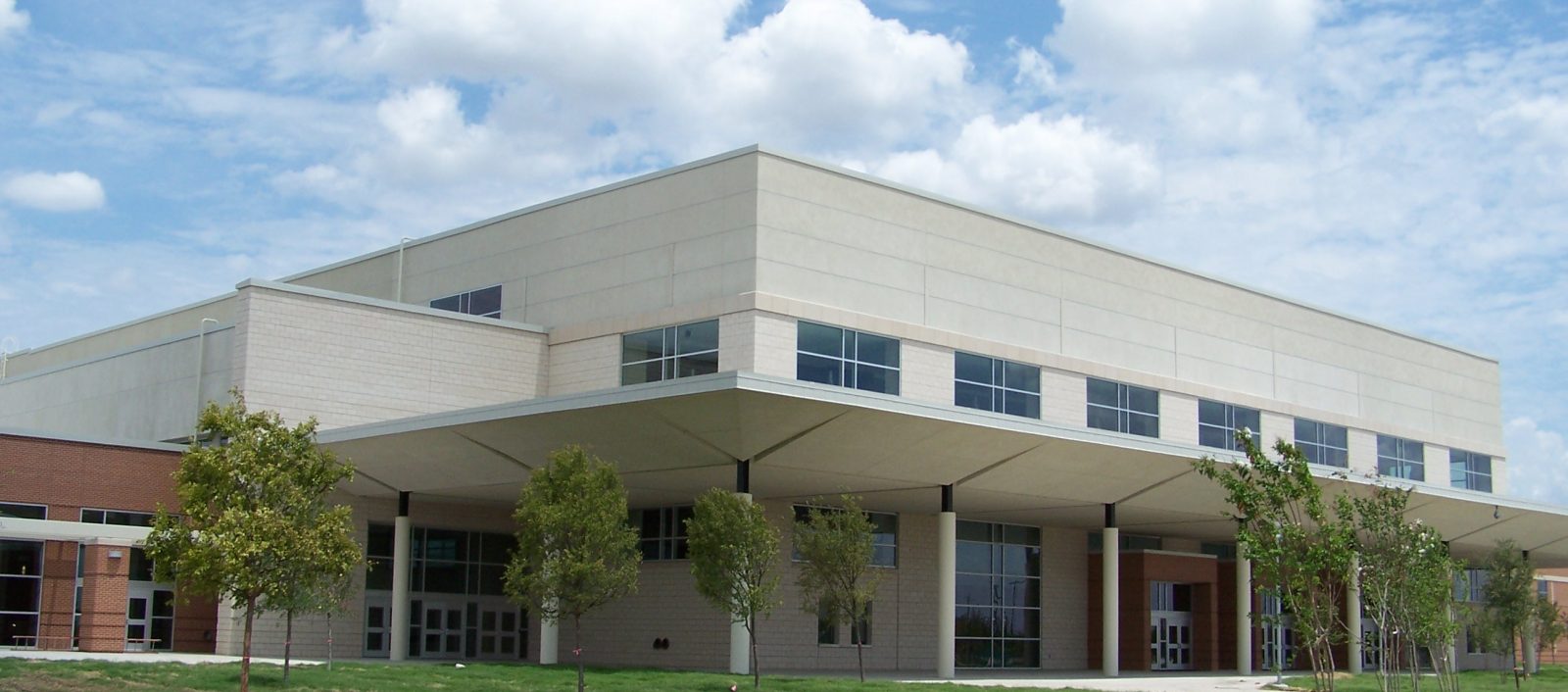 Exterior view of the Lancaster ISD High School entrance with modern architecture made of various materials.