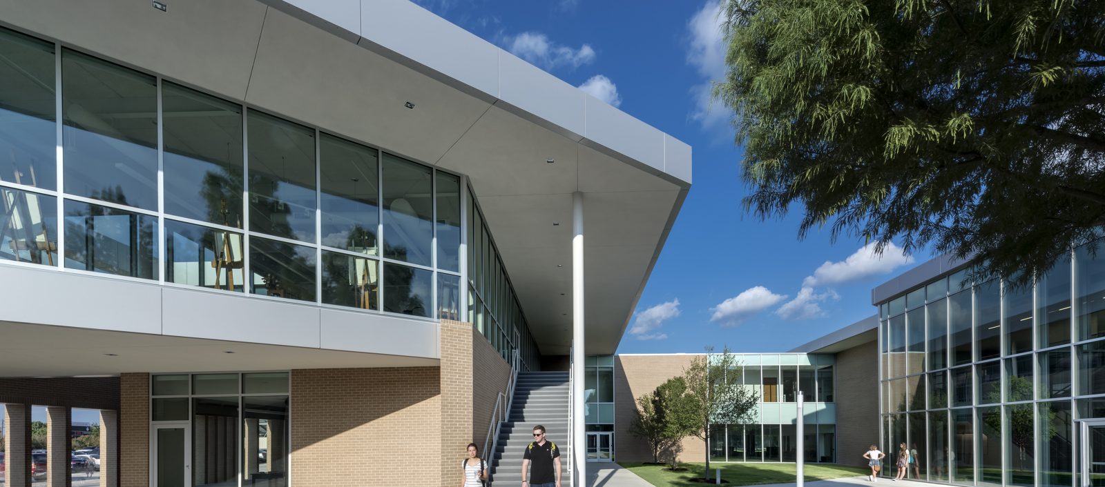 Exterior close-up view of Bishop Lynch High School entrance with modern design and students walking out.