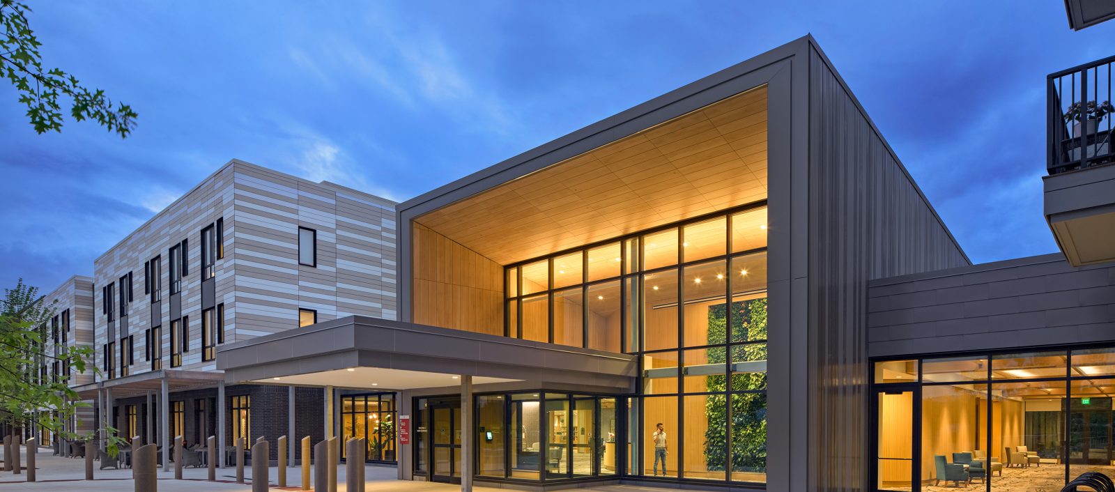 Exterior view of the entrance at the Baldwin in Londonderry, New Hampshire featuring illuminated windows and the entrance to the building.