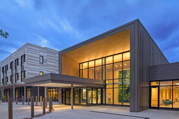 Exterior view of the entrance at the Baldwin in Londonderry, New Hampshire featuring illuminated windows and the entrance to the building.
