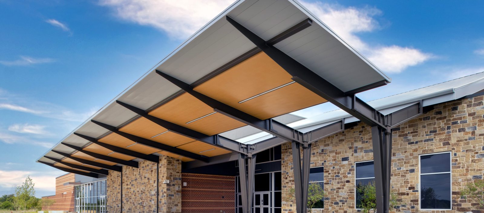 Exterior view of the Crowley Montessori Academy with modern architecture and large metal structure on the roof.