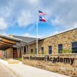 Exterior view of the front entrance at Crowley Montessori Academy with the school title written on top of stone facade.