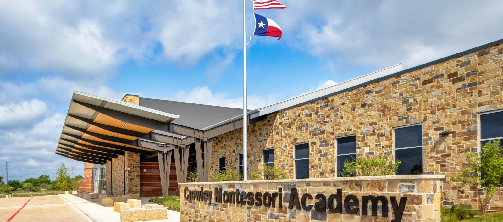 Exterior view of the front entrance at Crowley Montessori Academy with the school title written on top of stone facade.