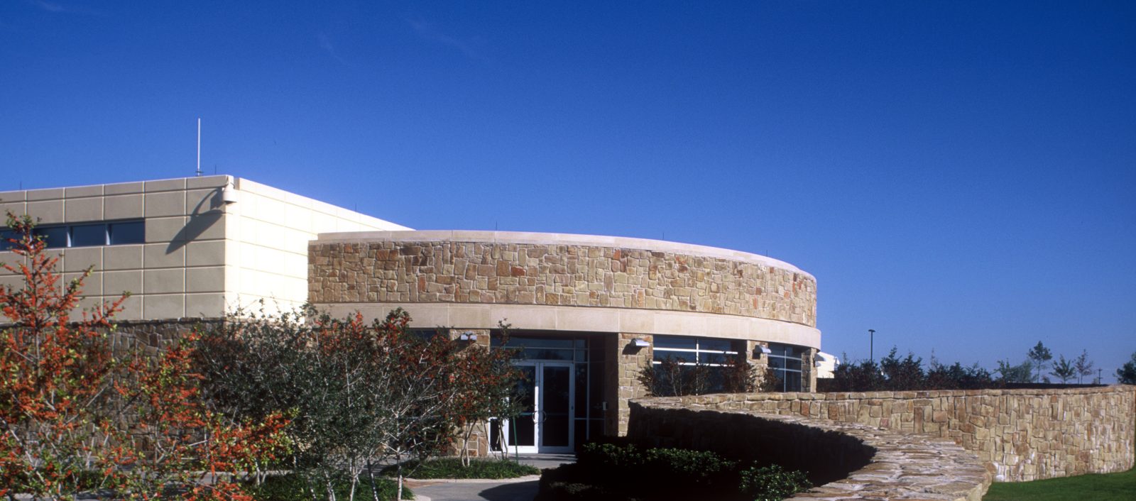 Exterior of Experian Data Center, a one story building also featuring stone wall, building, and grassy field