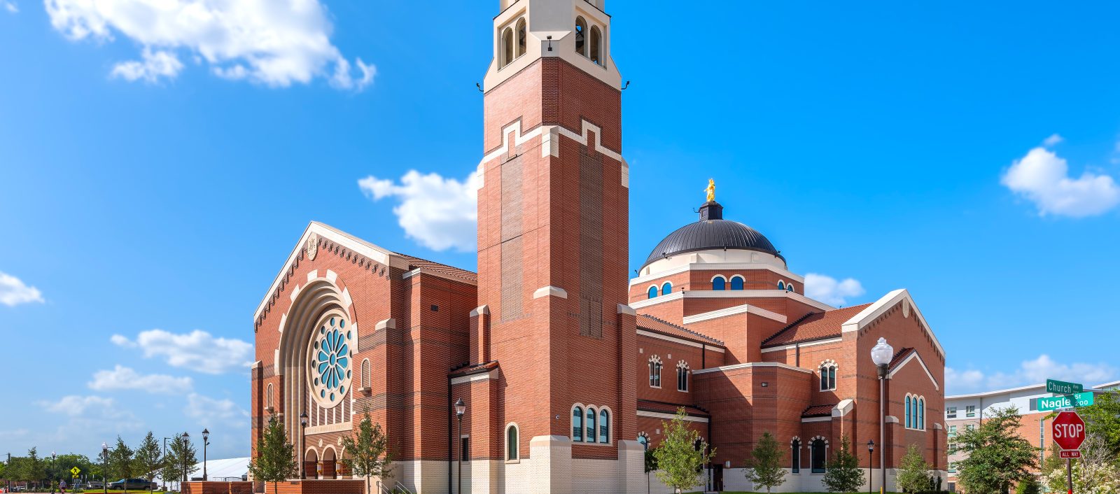 Exterior of St. Mary's Catholic Center, a large brick church with a prominent tower and dome, under a clear blue sky.